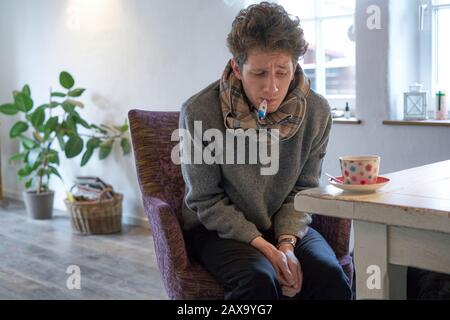 portrait de jeune étudiant malade froid épuisé est assis à la table dans son appartement devant une tasse de thé Banque D'Images