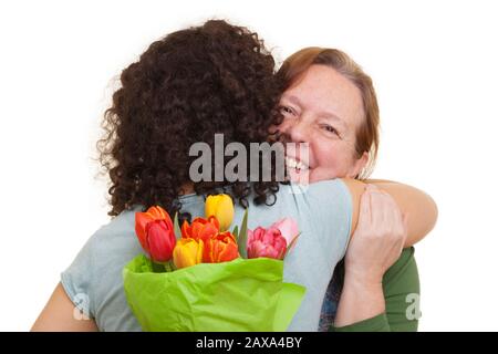 Jeune femme avec bouquet de tulipes dissimulées derrière sa femme âgée embrassant le dos, isolée sur fond blanc. Fête des mères, Saint Valentin, Pâques et Banque D'Images