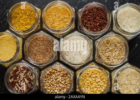 Vue de dessus des bocaux en verre avec diverses céréales, riz, couscous, boulgur et sarrasin. Banque D'Images