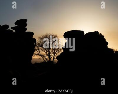 L'arbre d'hiver et les roches de pierre de gris ont été taillées contre un ciel coucher de soleil à Brimham Moor Nidhair AONB North Yorkshire England Banque D'Images