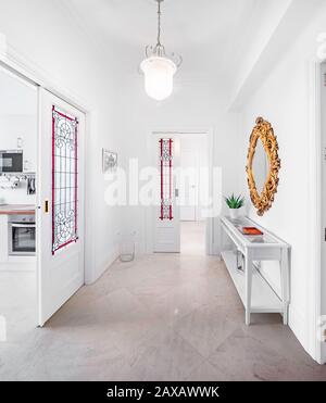 Chambre dans le hall à l'entrée d'un appartement moderne avec portes en vitrail. Hall lumineux dans un intérieur élégant avec miroir en bois doré Banque D'Images