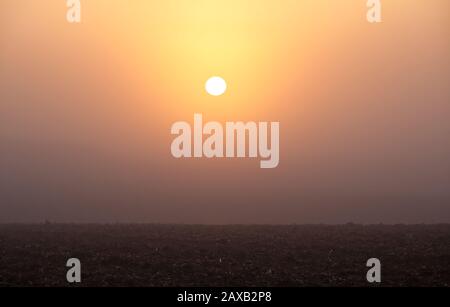 Lever du soleil brûlant à travers la brume du matin Banque D'Images