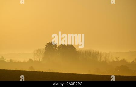 Lever du soleil brûlant à travers la brume du matin dans la vallée de Dropt près de Duras, Lot-et-Garonne, France Banque D'Images