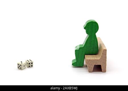 Homme figures en bois assis sur un banc avec des dés, concept, isolé sur un fond blanc Banque D'Images