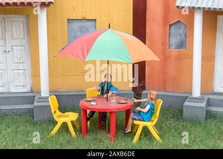 Une création Inspirée par les voyages de Gulliver par Jonathan Swift.Drôle image d'un Lilliput jouets est assis à une table de café dans la cour. Banque D'Images