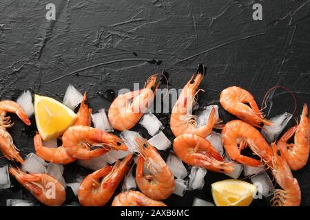 Crevettes, citron et glace sur fond noir, vue de dessus Banque D'Images