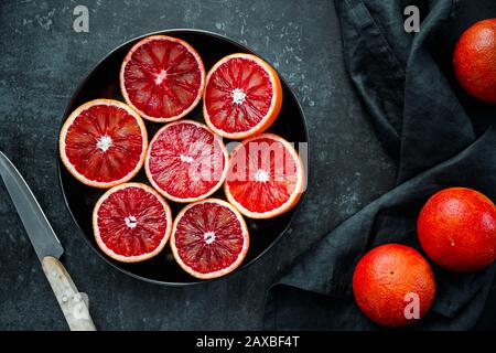 Oranges de sang coulées dans une plaque sur un fond bleu foncé. Banque D'Images