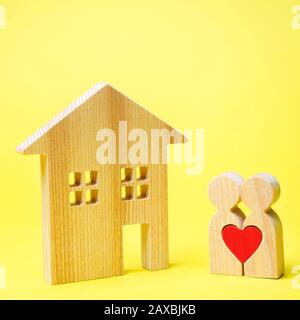 Quelques amoureux se tiennent près de la maison en bois. Saint Valentin. Logement abordable pour les jeunes familles. Propriété De Location. Hypothèque et prêt. Le Banque D'Images