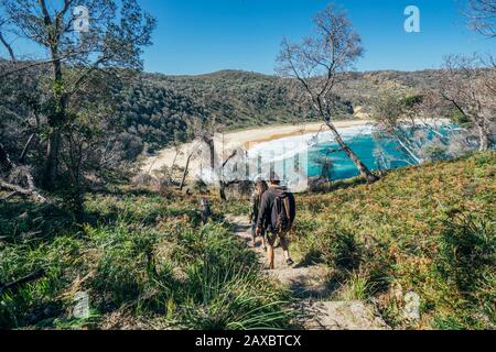 Hommes randonnée sur le chemin de la plage ensoleillée de l'océan à distance Jervis Bay Australie Banque D'Images