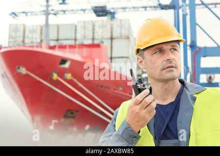 Placer le travailleur sur le quai en utilisant le talkie-walkie sous le bateau à conteneurs du chantier naval Banque D'Images