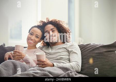 Portrait souriant, couple affectueux se reposant sur un canapé Banque D'Images