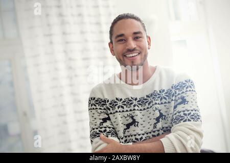 Portrait souriant, confiant jeune homme dans le pull de Noël Banque D'Images