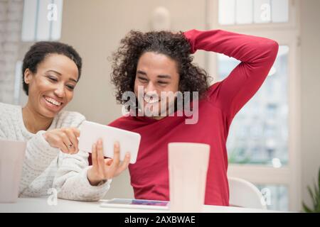 Heureux couple utilisant le smartphone à la table Banque D'Images