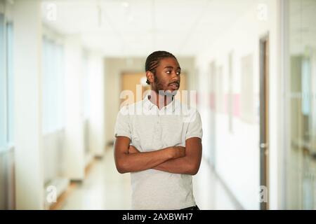 Portrait confiant jeune homme avec des bras croisés dans le couloir Banque D'Images