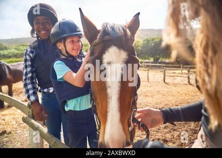 Joyeuses filles apprennent à cheval à cheval dans le paddock ensoleillé Banque D'Images