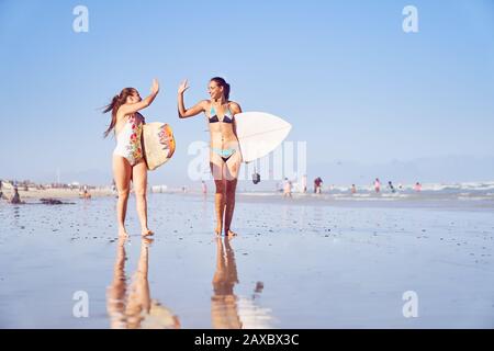 Joyeuses jeunes filles surfent amis haut fiving sur la plage ensoleillée Banque D'Images