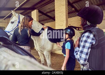 Instructeur féminin aidant les filles à se préparer à l'équitation Banque D'Images