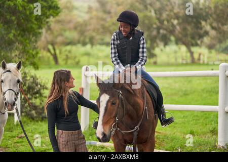 Une femme instructeur d'équitation d'enseignement à une fille en paddock rural Banque D'Images