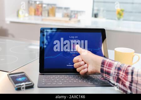 Perspective personnelle homme se connectant à une tablette numérique avec empreinte digitale dans la cuisine Banque D'Images