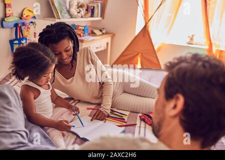 Jeunes enfants de la famille coloriant sur le lit Banque D'Images