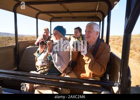 Joyeuses personnes âgées avec jumelles et appareil photo lors d'un safari en véhicule tout-terrain Banque D'Images