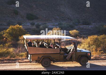 Safari guide et groupe en véhicule tout-terrain sur route ensoleillée Banque D'Images