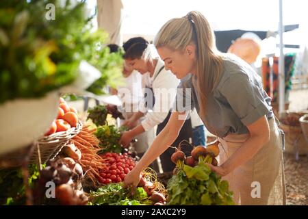 Femme travaillant, organisant des produits sur le marché des agriculteurs Banque D'Images