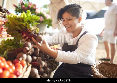 Sourire jeune femme travaillant, organiser des produits sur le marché des agriculteurs Banque D'Images