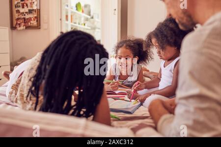 Jeunes enfants de la famille coloriant sur le lit Banque D'Images