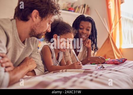 Jeunes enfants de la famille coloriant sur le lit Banque D'Images