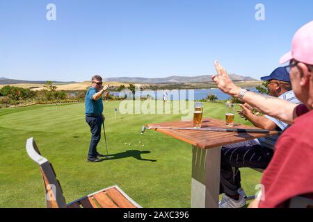 Des amis golfeurs masculins boivent de la bière et pratiquent la mise Banque D'Images