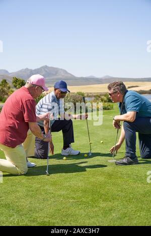 Les golfeurs masculins s'agenouillent sur le vert d'exercice Banque D'Images