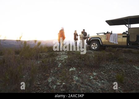 Safari groupe boire du thé à l'extérieur du véhicule tout-terrain au lever du soleil Banque D'Images