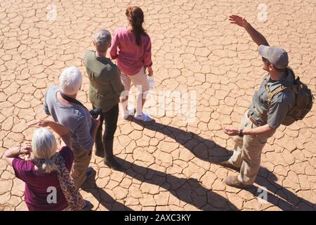 Guide de visite Safari parlant avec le groupe sur terre fissurée ensoleillée Banque D'Images