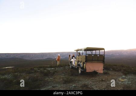 Safari en groupe et en véhicule tout-terrain sur une colline à distance au lever du soleil Banque D'Images