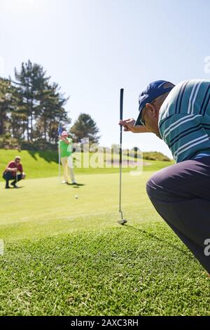 Le golfeur masculin se prépare à prendre le cliché sur le vert d'exercice ensoleillé Banque D'Images