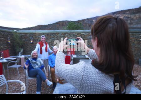 Femme avec téléphone photo photographier des amis seniors sur le patio de l'hôtel Banque D'Images
