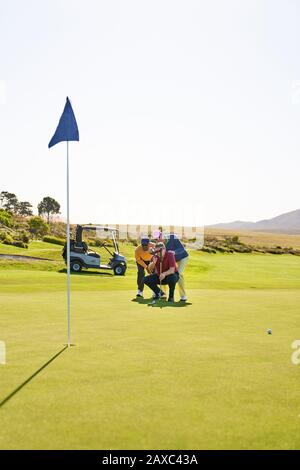 Les golfeurs de sexe masculin planifient le putt tourné sur le terrain de golf ensoleillé vert d'exercice Banque D'Images