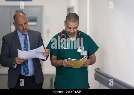 Administrateur masculin et chirurgien lisant les documents administratifs dans le couloir de l'hôpital Banque D'Images