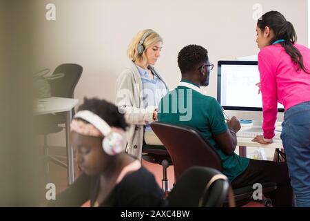 Un instructeur d'université communautaire aide les étudiants dans les ordinateurs en salle de classe de laboratoire informatique Banque D'Images