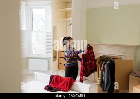 Femme déballant les vêtements de la boîte en mouvement dans la chambre Banque D'Images