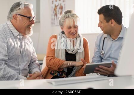 Médecin avec tablette numérique réunion avec couple dans le bureau de médecins Banque D'Images