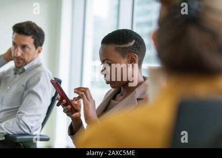Femme d'affaires utilisant un smartphone dans la salle de conférence Banque D'Images
