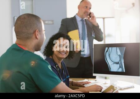 Portrait infirmière féminine confiante examinant la radiographie numérique avec un collègue en clinique Banque D'Images