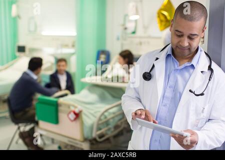 Médecin masculin avec tablette numérique en train de faire des rondes dans le service hospitalier Banque D'Images