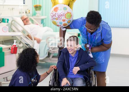 Médecin et infirmière parlant avec un jeune patient en fauteuil roulant dans le service hospitalier Banque D'Images