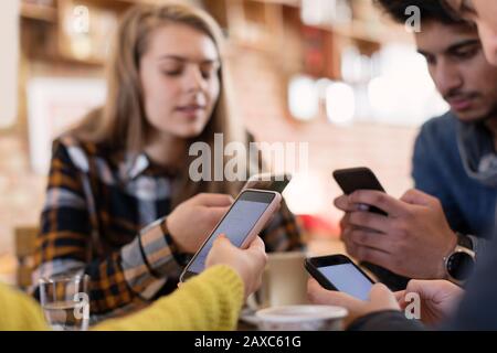 Jeunes amis adultes utilisant des smartphones dans un café Banque D'Images