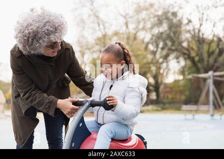 Grand-mère jouant avec la petite-fille à l'aire de jeux Banque D'Images