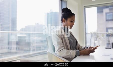 Femme d'affaires utilisant un smartphone dans la salle de conférence urbaine Banque D'Images