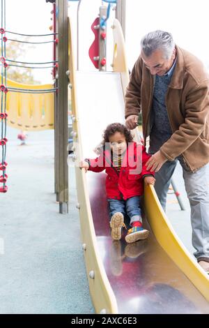 Grand-père jouant avec un petit-fils sur la piste de jeu Banque D'Images
